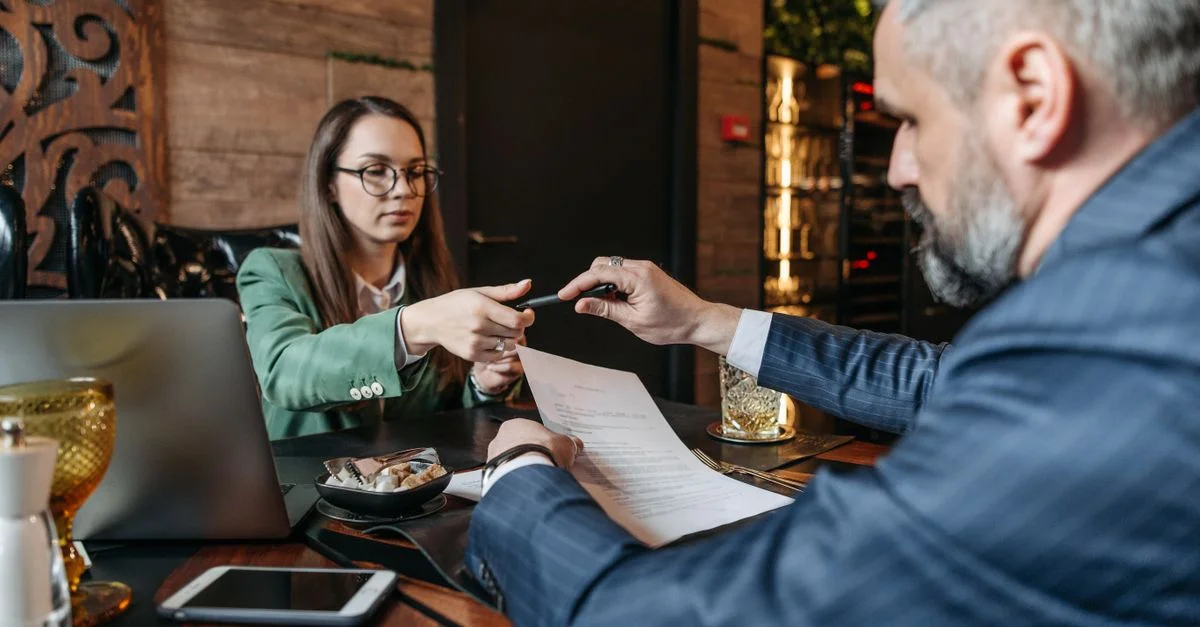 Un homme et une femme examinent et signent un contrat d'affaires dans un café élégant.
