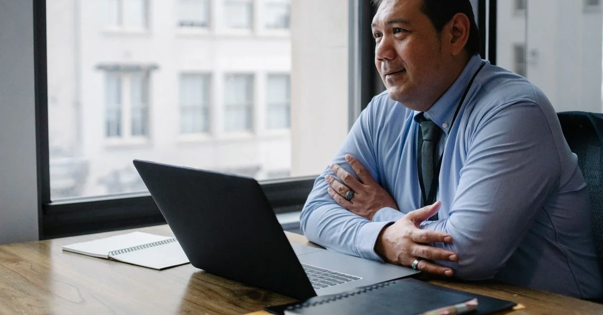 Homme d'affaires confiant en tenue formelle utilisant un ordinateur portable dans un cadre de bureau moderne.